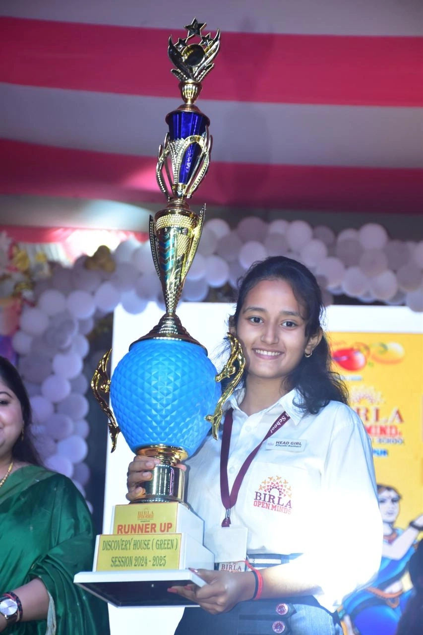 A senior student holding the inter-school house trophy at BOMIS Naubatpur