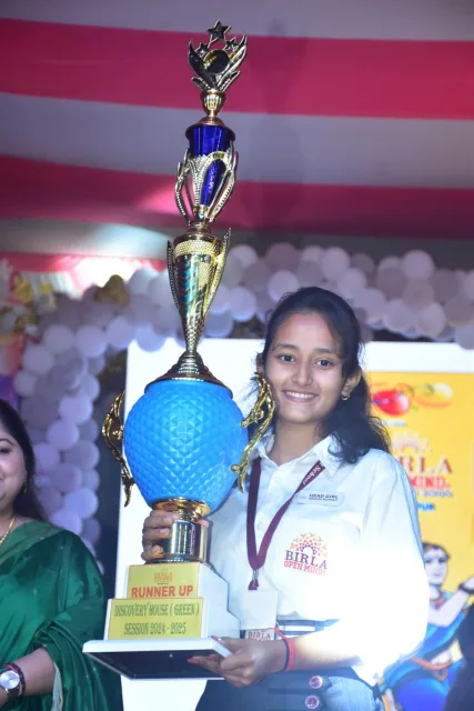 A senior student holding the inter-school house trophy at BOMIS Naubatpur